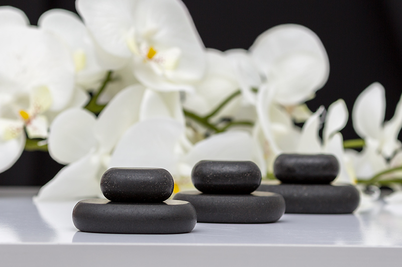 Steine vor Orchideen Hot Stone Massage